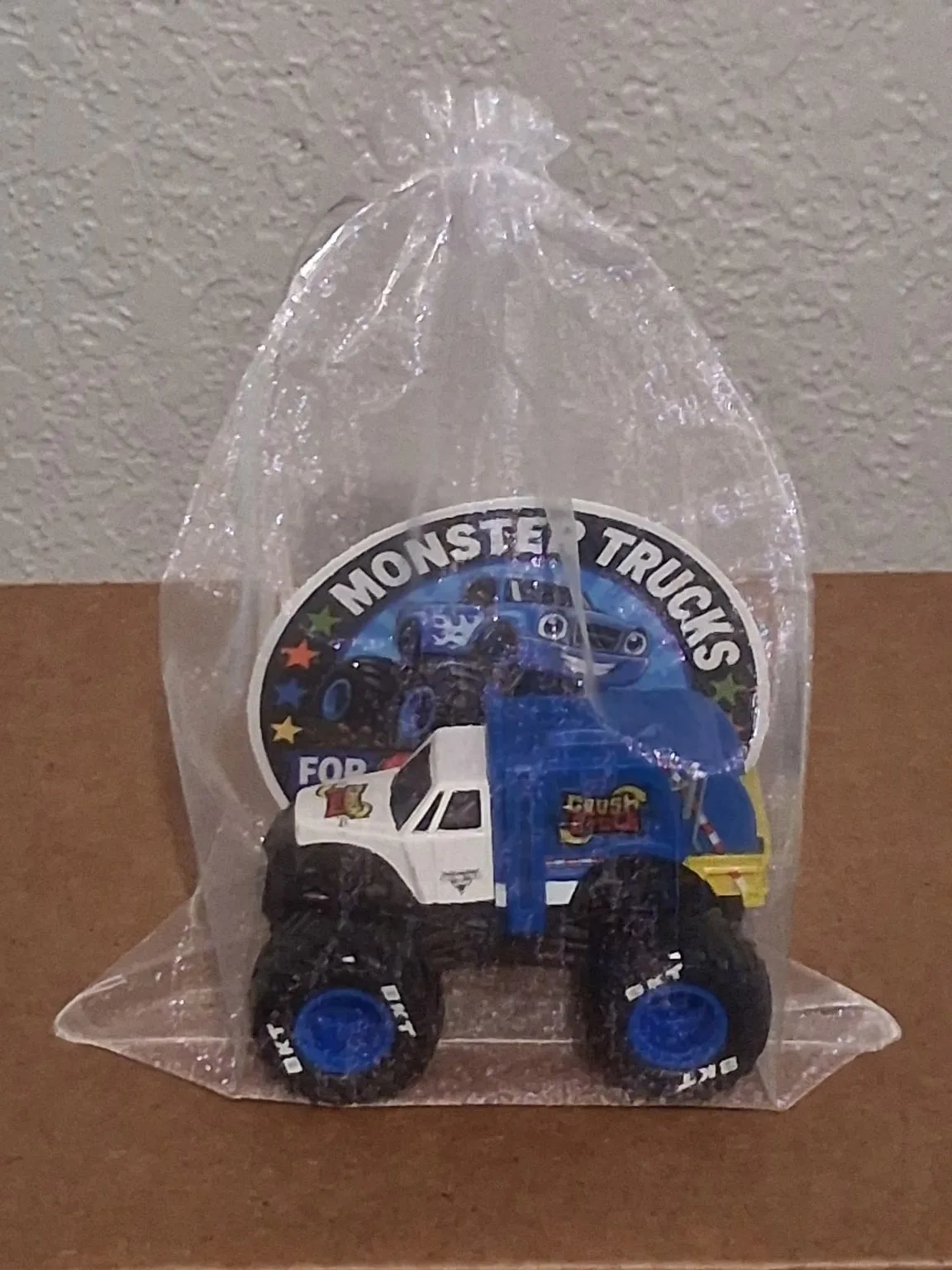 Blue and white toy monster truck prepared in clear packaging
